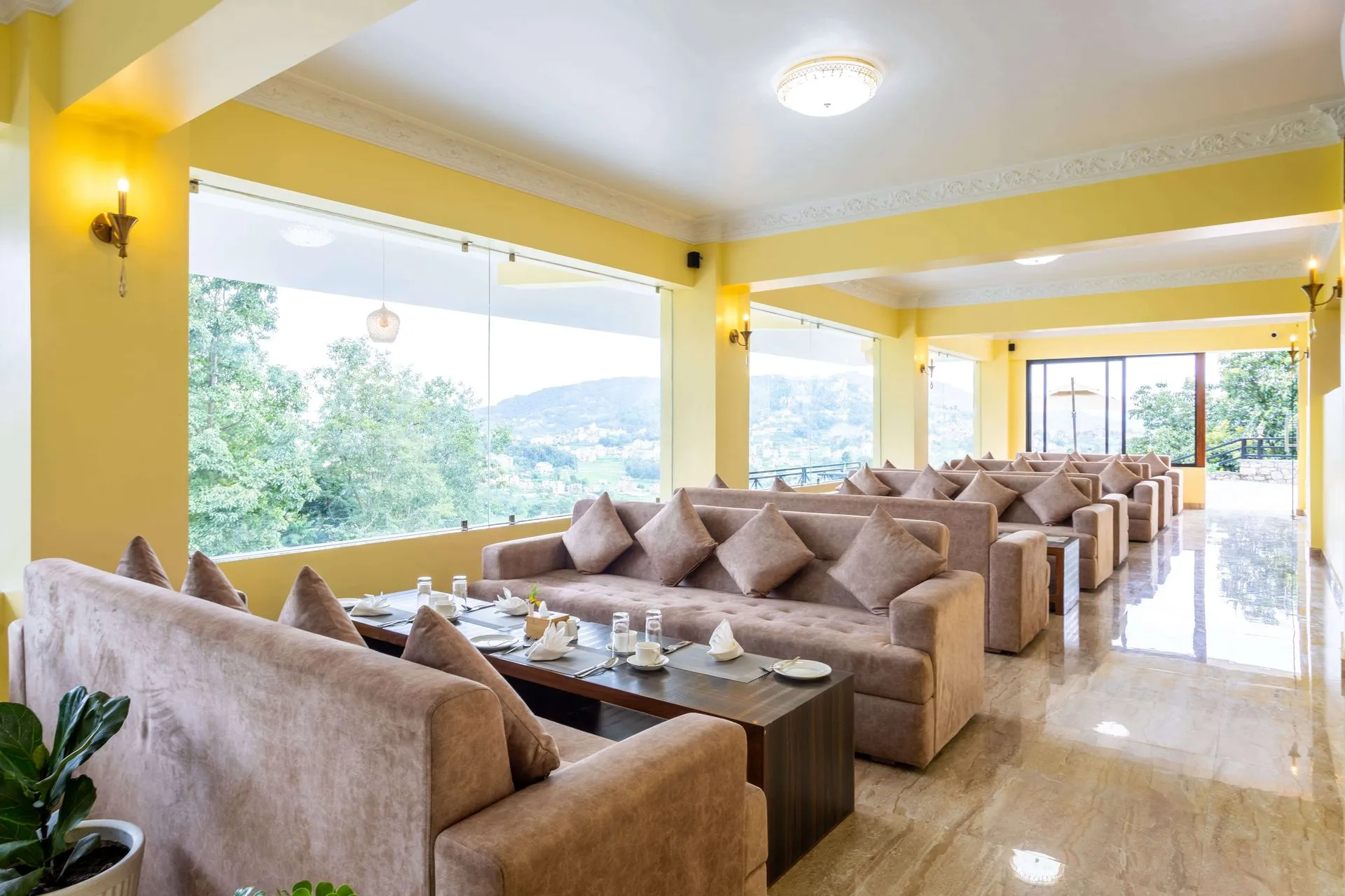 The cafe's lounge seating in rows of tan sofas beneath yellow walls, picture windows onto the valley trees