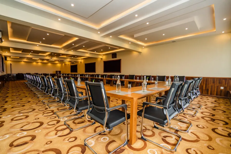 Rosewood in a long U-shape of about forty seats, black mesh chairs along both arms, dark acoustic panels and a coffered ceiling