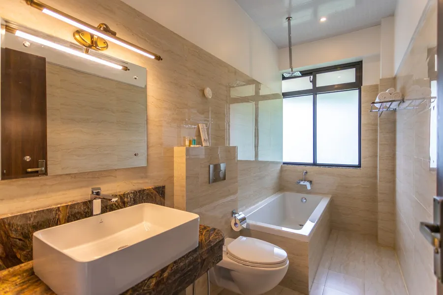 The suite bathroom: a freestanding basin on a stone counter and a bathtub under the window