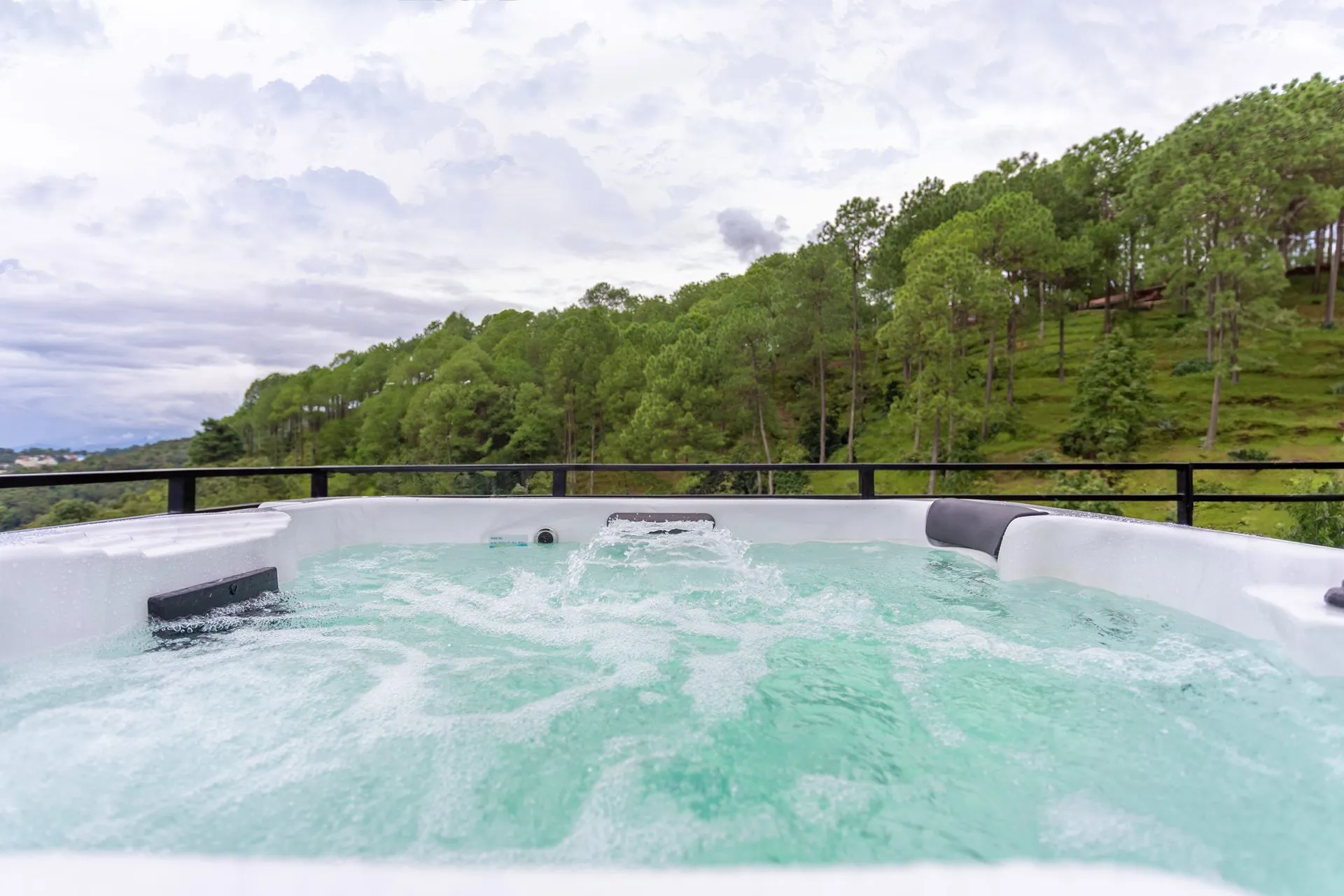 The rooftop jacuzzi bubbling against the forested hillside