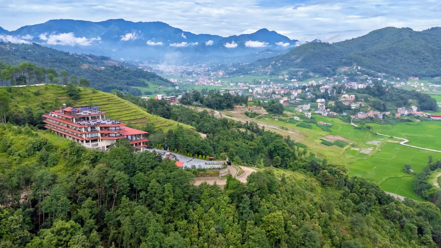 The resort from the air on its forested ridge, red roofs above the drive's switchbacks, the valley town and mountain ranges layered beyond