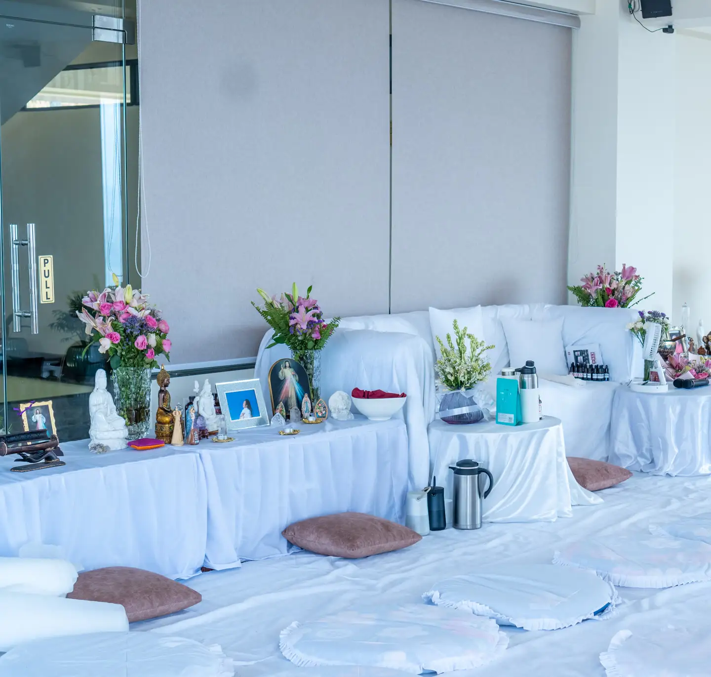 A mindfulness space at the resort dressed for a session: white-draped tables carrying flowers and statues, mats and cushions laid out on the floor